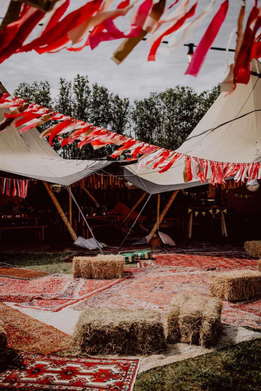 Hochzeitsdekoration mit Strohballen, Perser-Teppichen, Zelten und Fahnen. Alles in Rot-Weiß Tönen