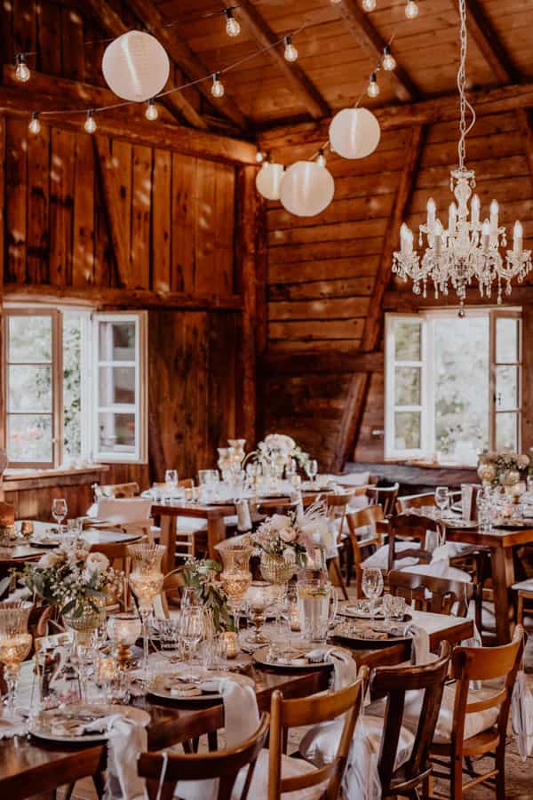 Für eine Hochzeit gedeckter Tisch mit weiß brauner Dekoration in der Scheune im Gauklerhof Allgäu