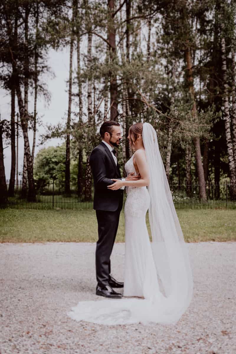 Brautpaar steht zusammen auf Gut Ammerhof. Im Hintergrund sieht man Bäume