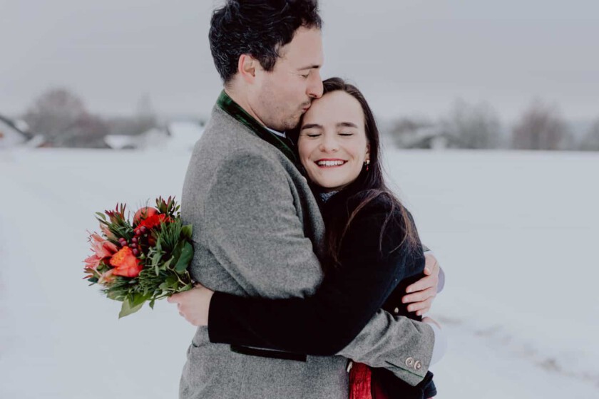 Ein Paar umarmt sich während des Paarshootings. Sie stehen in einer verschneiten Landschaft.