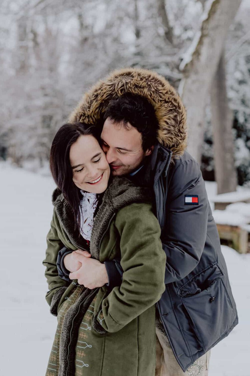 Paar umarmt sich beim Paarshooting. Sie haben Winterjacken an.