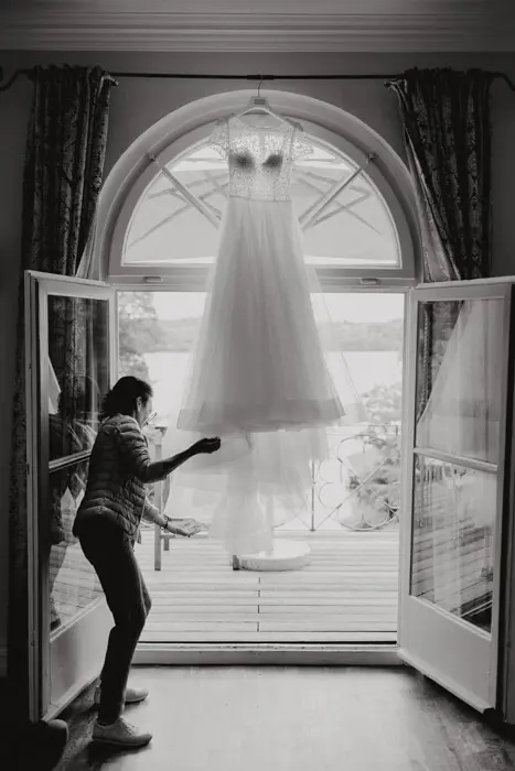 Hochzeitsfotograf Bayern Brautkleid hängt vor Balkon, Vorbereitungen für Hochzeit Dokumentarische Editorial Hochzeitsfotografie