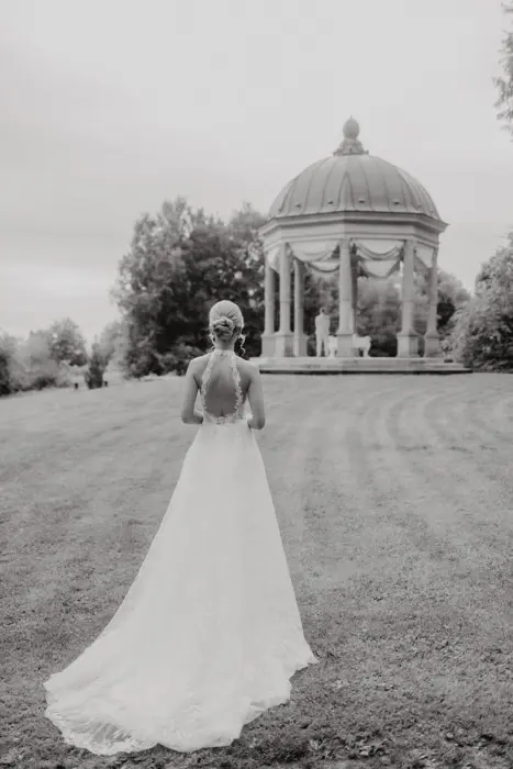 Hochzeitsfotograf Bayern Braut in weißem Kleid vor einem romantischen Pavillon im Freien Dokumentarische Editorial Hochzeitsfotografie